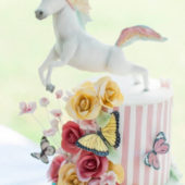 Jumping unicorn birthday cake with flowers and butterflies